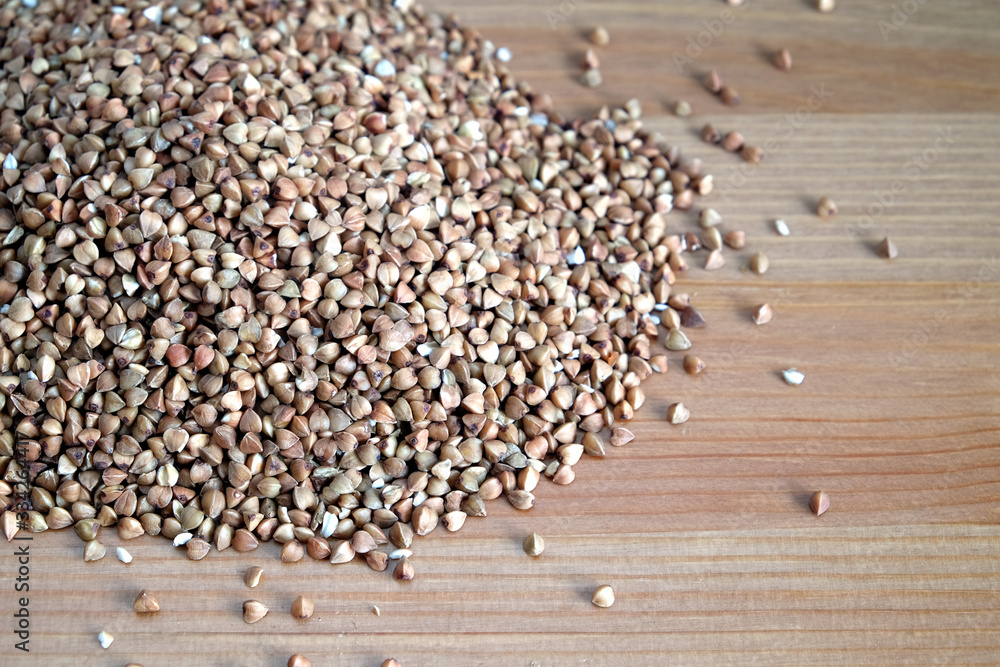 Heap of many buckwheat grains on wooden table surface indoors front view close up Heap of many buckwheat grains on wooden table surface indoors front view close up