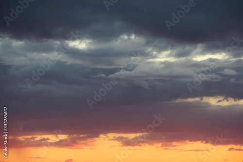 Clouds in the blue sky at sunset or dawn backlit by the sun. Place for text and design. © Stanislav