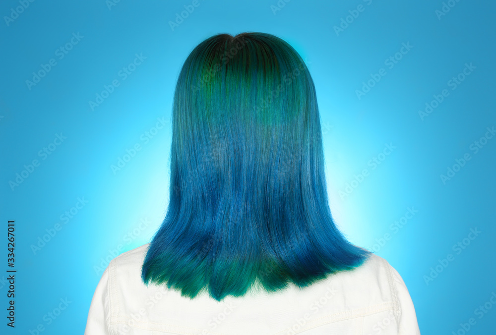 Naklejka premium Woman with bright dyed hair on light blue background, back view
