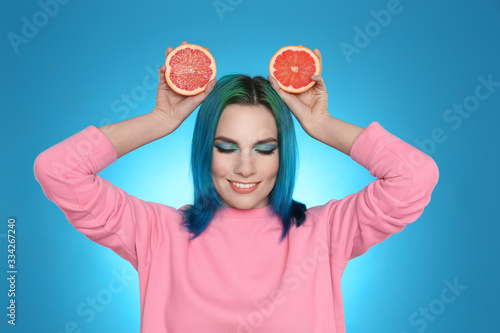 Wallpaper Mural Young woman with bright dyed hair holding grapefruit on light blue background Torontodigital.ca