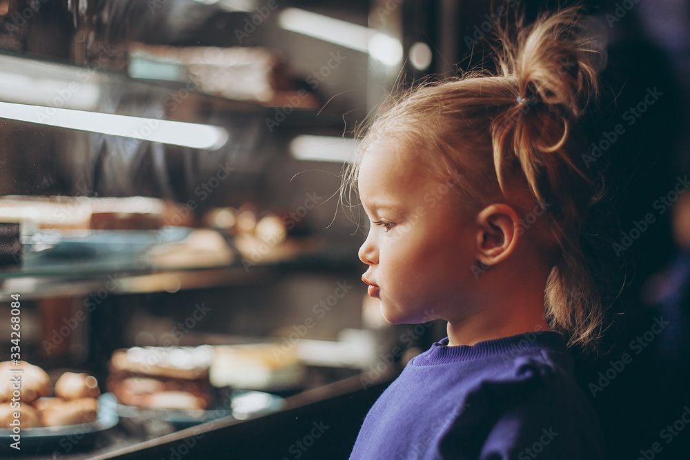 lovely girl admiringly examines a lighted showcase with various delicious cakes and desserts lovely girl admiringly examines a lighted showcase with various delicious cakes and desserts