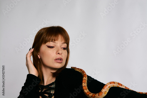 Beautiful woman in black bodywear and snake. Ginger model girl with fashion perfect make up.