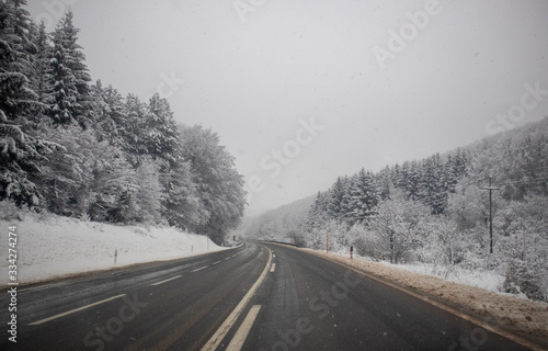 Snow on the road at winter. Trees covered with snow next to the road. Cestobrodica in Serbia. © Milan