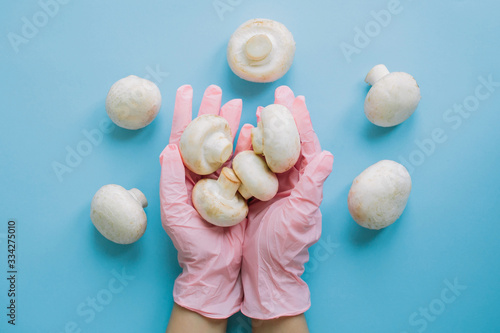 Safe shopping in quarantine. Hands in pink glove holding mushrooms on blue background flat lay. Order groceries and get them delivered safe during virus epidemic. Stay home Stay safe.