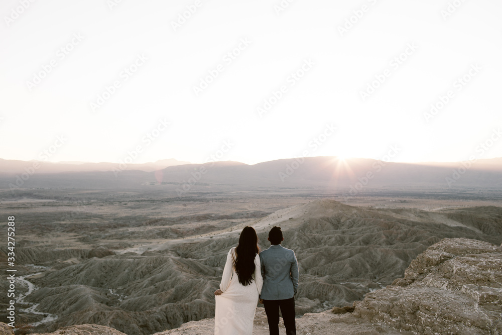 man and woman looking out across a desert vista as the sun sets