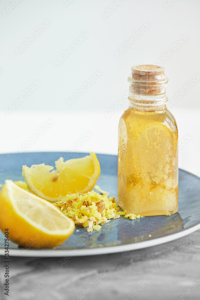 Yellow juicy Lemon, shredded Ginger and Honey on blue plate for homeopathic mixture to treat flu virus symptoms on white background Yellow juicy Lemon, shredded Ginger and Honey on blue plate for homeopathic mixture to treat flu virus symptoms on white background
