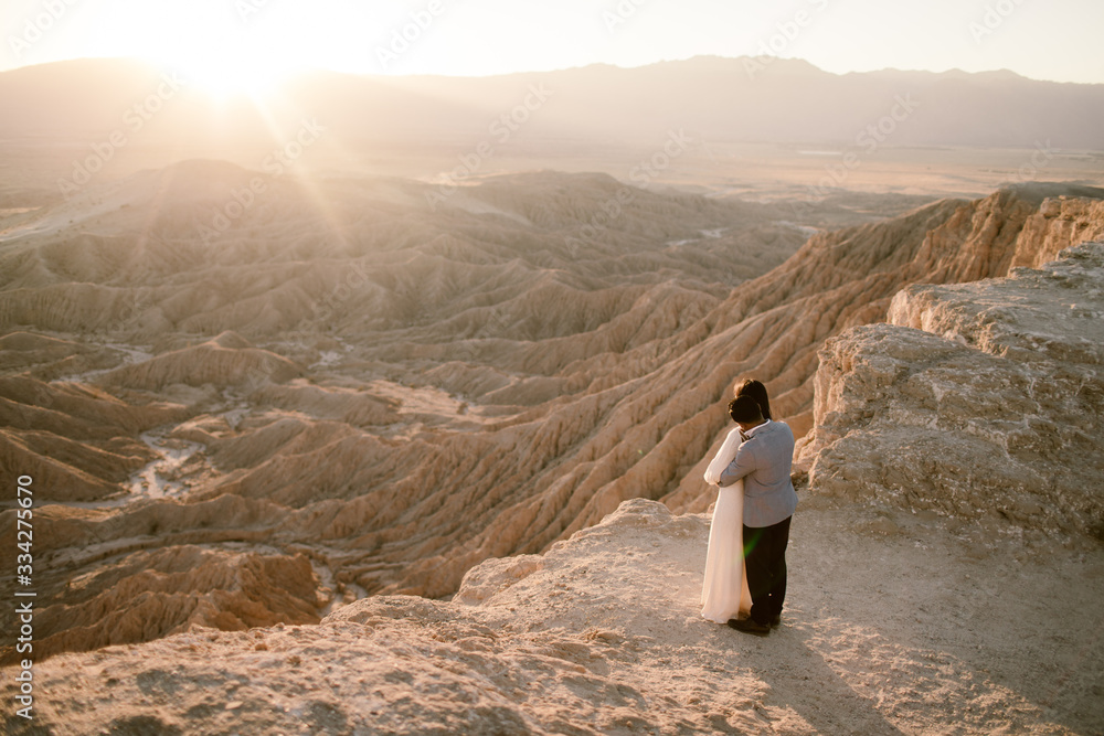 man and woman holding each other at a desert overlook
