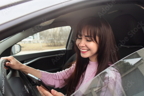 Happy brunette in a car with a phone