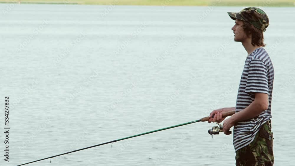 Young man in the boat on the lake with a rod while fishing. Outside. Young man in the boat on the lake with a rod while fishing. Outside.