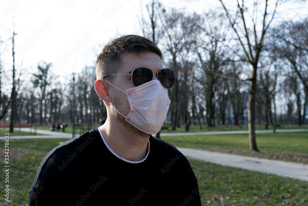 A man in a medical mask on the street. The head of a man in a t-shirt and black glasses on the street. Quarantine. Pandemic. Coronavirus. Vaccines. Covid-19 A man in a medical mask on the street. The head of a man in a t-shirt and black glasses on the street. Quarantine. Pandemic. Coronavirus. Vaccines. Covid-19