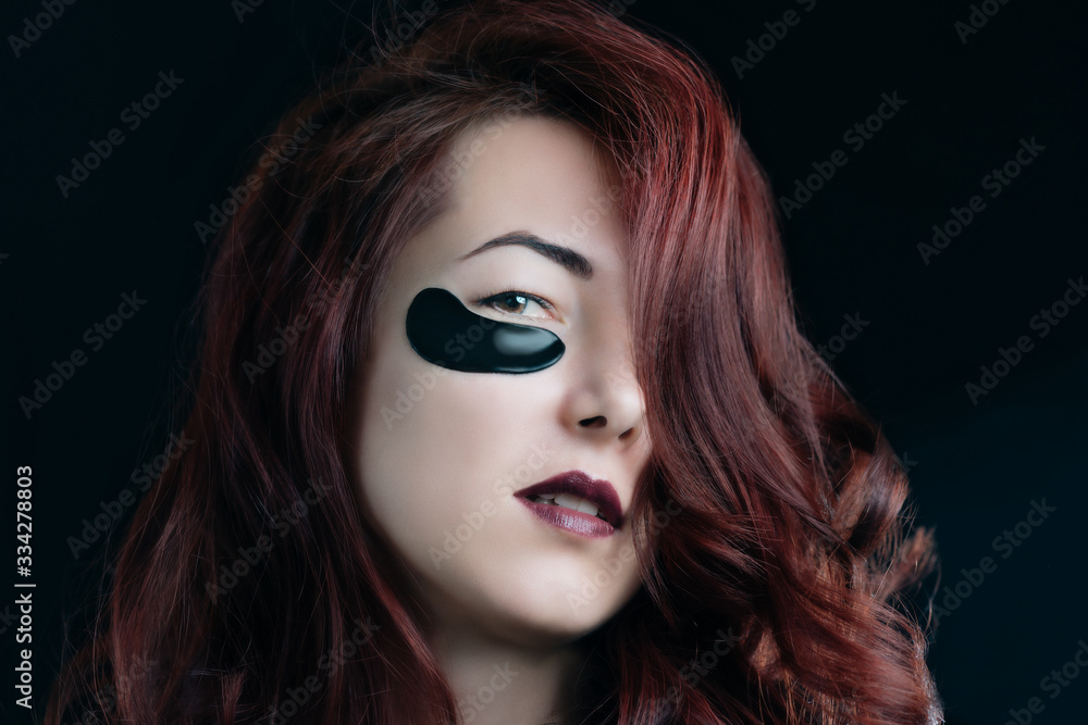 Attractive woman with make-up and black hydrogel patches.
