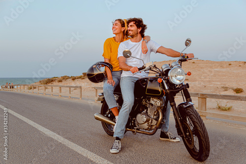 young couple on motorcycle on a road traveling to the beach