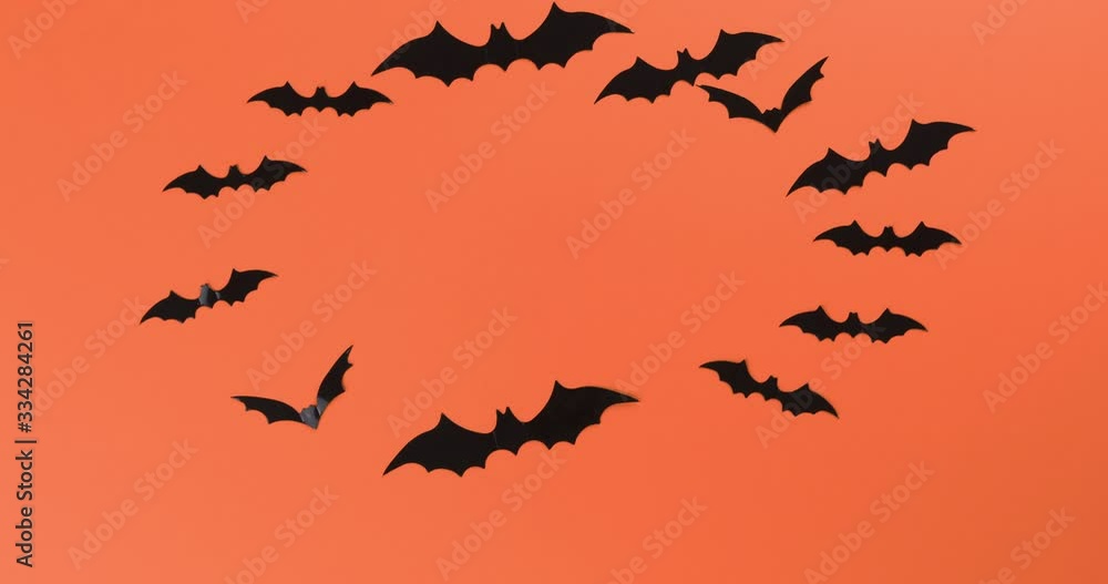 Halloween concept with many black horrible bats flying in a circle. Scary halloween stop motion footage on orange background Halloween concept with many black horrible bats flying in a circle. Scary halloween stop motion footage on orange background
