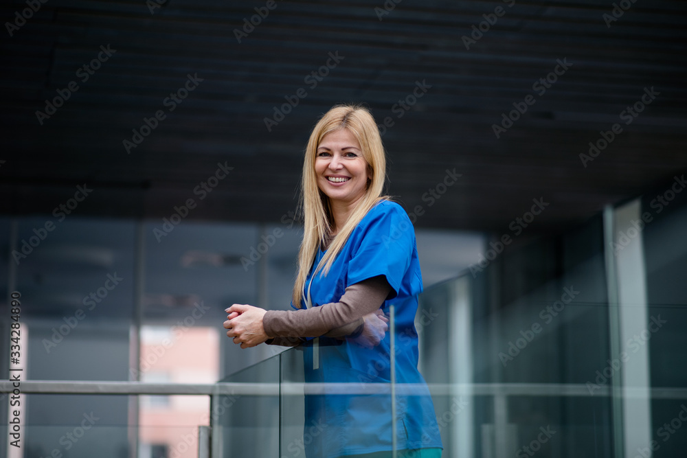 Portrait of doctor standing in hospital , leaning on glass railing.