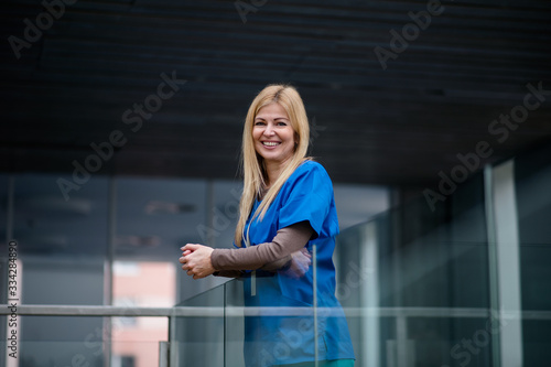 Portrait of doctor standing in hospital , leaning on glass railing.