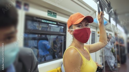 Woman travel caucasian ride at overground train airtrain with wearing protective medical red mask. Girl tourist at airtrain with respirator. Pandemic virus Coronavirus covid-19. People in mask. photo