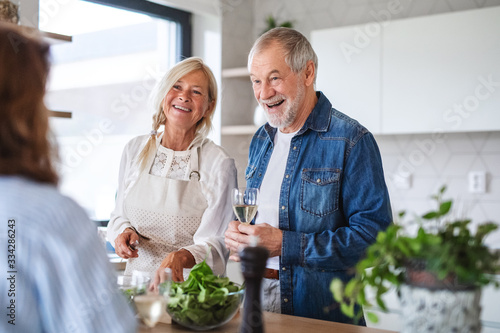 Group of senior friends at dinner party at home, cooking.