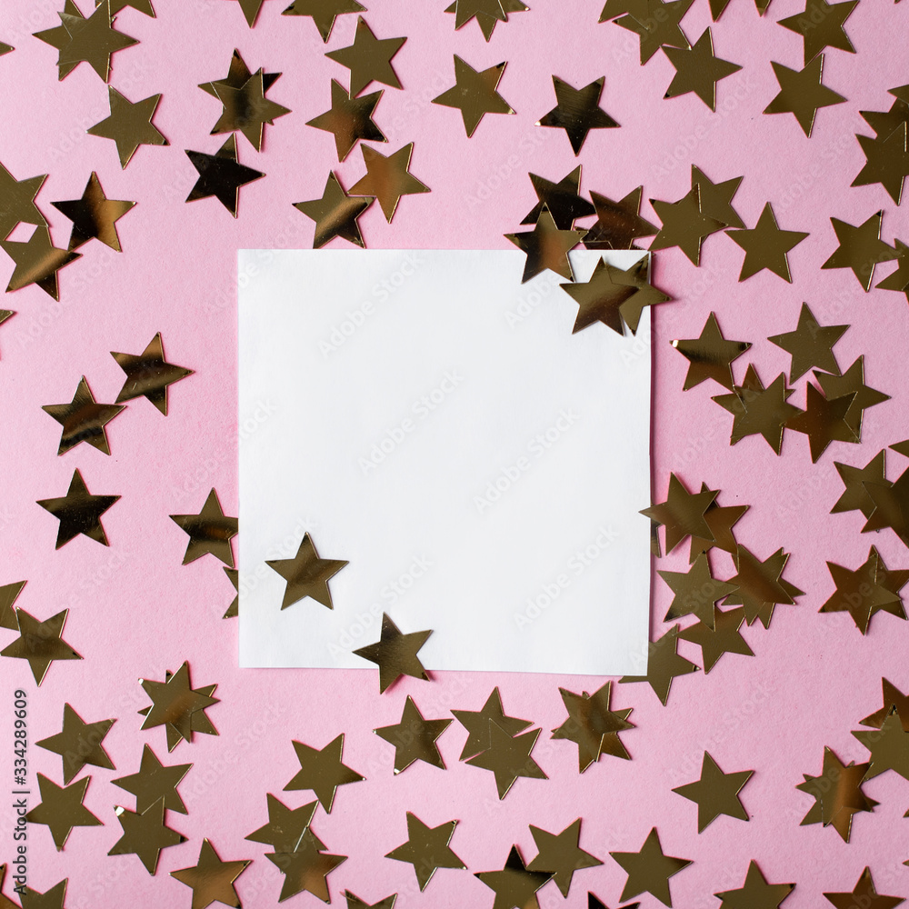Greeting card with sequins for the inscription, a blank square white sheet of paper, gold sparkles in the shape of stars, top view, pink background, frame for an inscription, copy space, flat lay