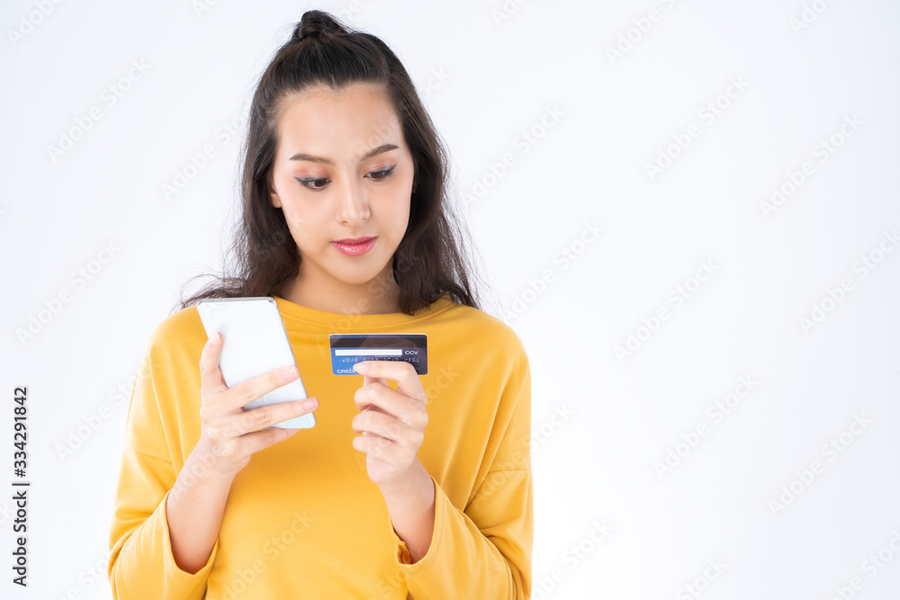 Young beauty Asian woman shopping payment online with credit card on smartphone and she wearing a yellow sweater shot isolated on white background Young beauty Asian woman shopping payment online with credit card on smartphone and she wearing a yellow sweater shot isolated on white background