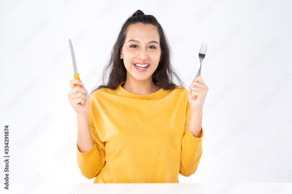 Young beauty Asian woman showing Knife Fork prepare to eat food and she wearing a yellow sweater shot isolated on white background Young beauty Asian woman showing Knife Fork prepare to eat food and she wearing a yellow sweater shot isolated on white background
