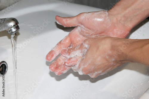  Hands wash with soap over a white sink