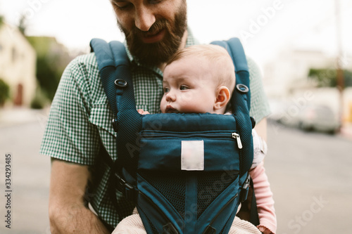 Obraz na plátně Baby girl being carried by her father in a carrier