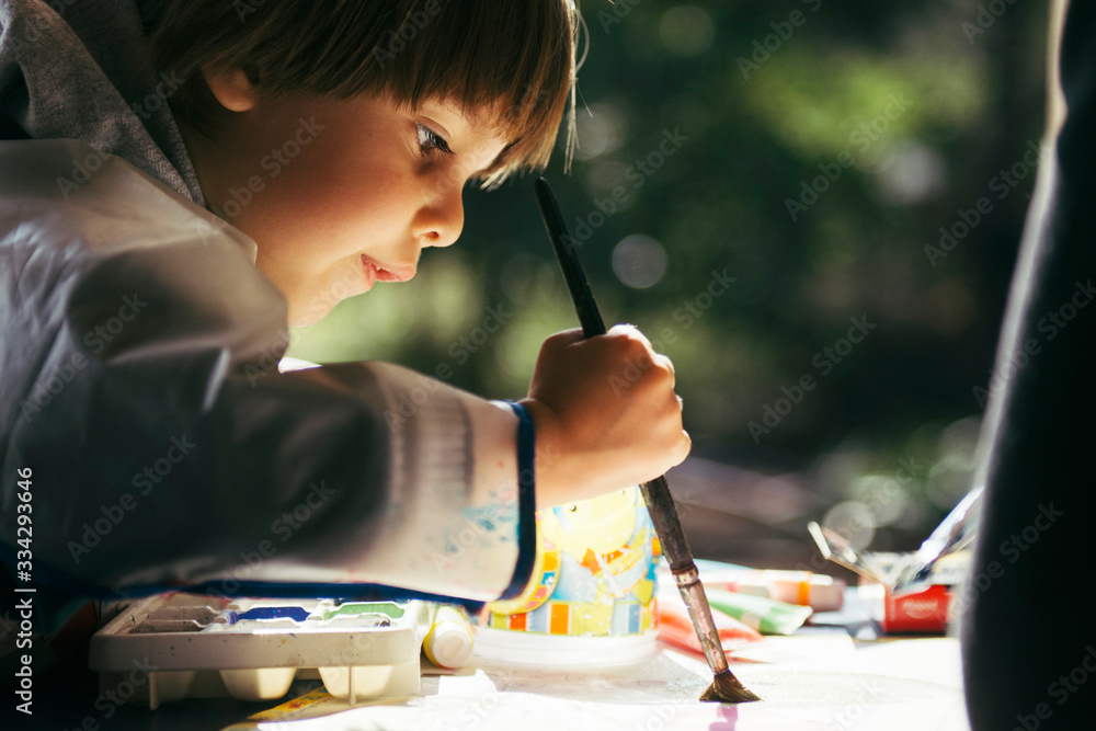 Niño haciendo actividades artisticas con pincel y pinturas - obrazy, fototapety, plakaty 