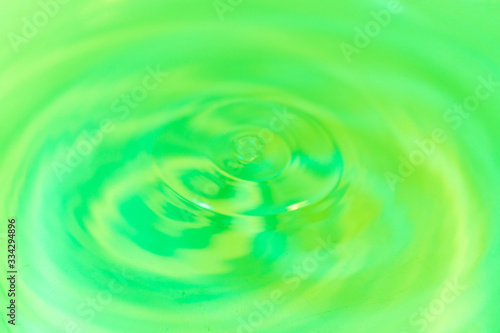 Closeup to water drops making circles on the surface. Amazing lime color background. Natural beauty.