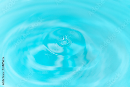 Closeup to water drops making circles on the surface. Amazing blue color background. Natural beauty.