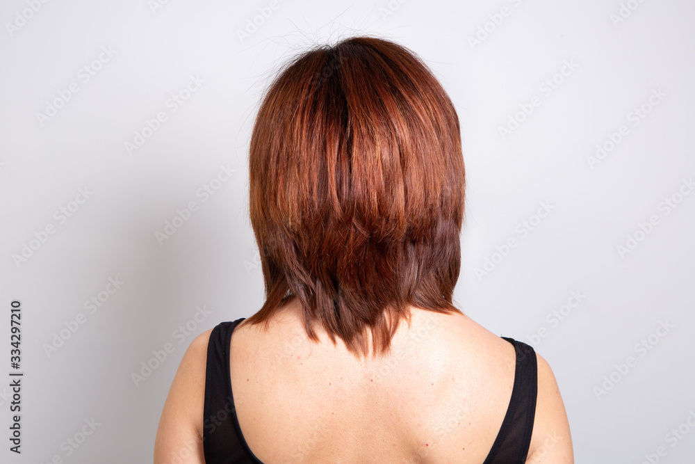 Smooth red-haired woman shot from behind, concept of hair care and physical appearance Smooth red-haired woman shot from behind, concept of hair care and physical appearance