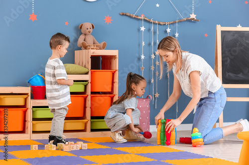 Nanny and cute little children playing at home photo