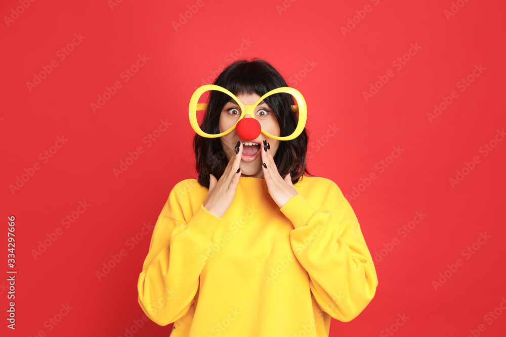 Emotional woman with large glasses and clown nose on red background. April fool's day Emotional woman with large glasses and clown nose on red background. April fool's day