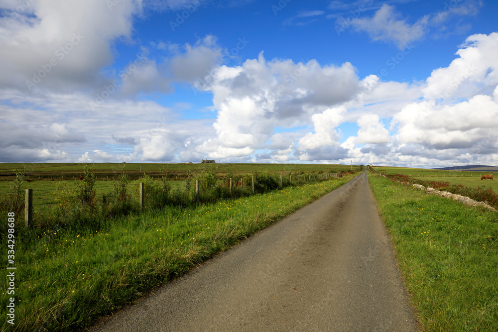 Orkney (Scotland), UK - August 09, 2018: A typical road in the Orkney islands, Orkney, Scotland, Highlands, United Kingdom Orkney (Scotland), UK - August 09, 2018: A typical road in the Orkney islands, Orkney, Scotland, Highlands, United Kingdom