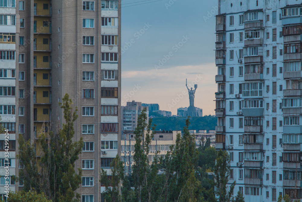 Socialistic or soviet apartment blocks in Kiev and visible the Motherland monument standing in between the both blocks in early evening.