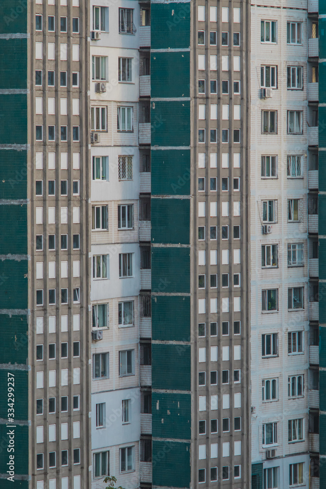 Typicial socialistic or soviet apartment blocks in a city, decaying facade in green and white color, Tiles are missing from time to time. Old apartment block from the eighties