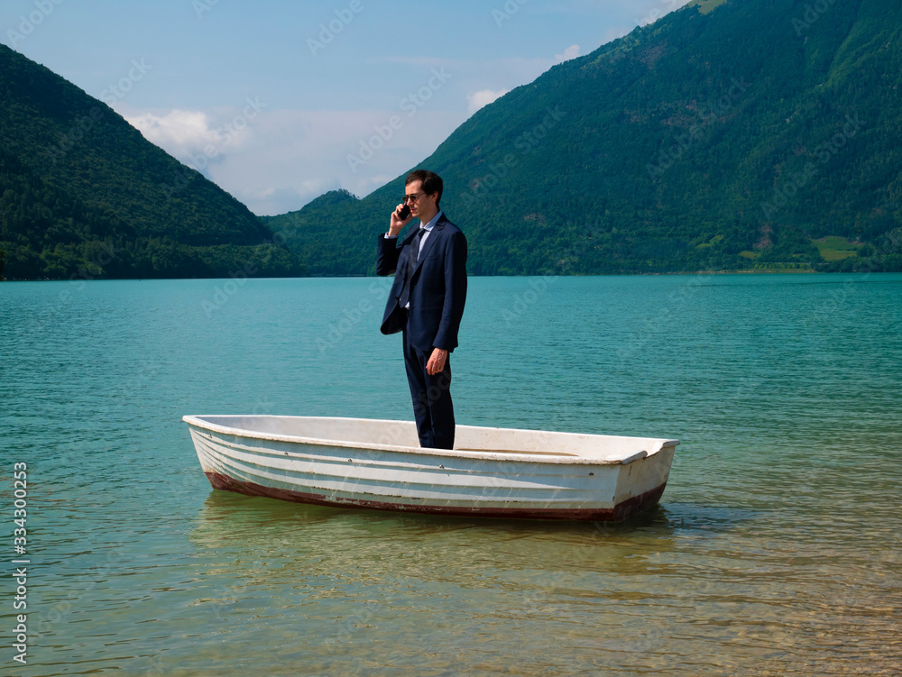 Man in suit on a small boat, uses the smartphone to call