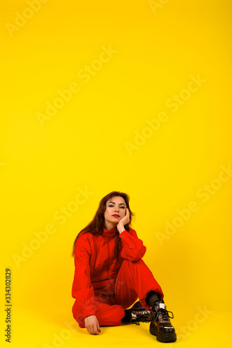 Modern girl in red overalls in the style of the 90s oversized clothes on a yellow background, expressive pose, fashion photo, trend 2020 © Nabokov Alex