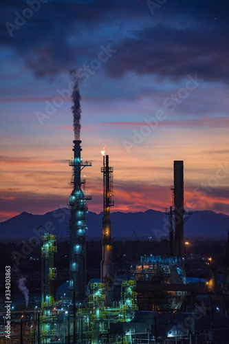 Steam Smokestack and Flame at Refinery with Mountains and Sunset