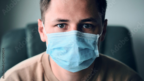 Close-up portrait of young man wearing medical mask and looking at the camera.