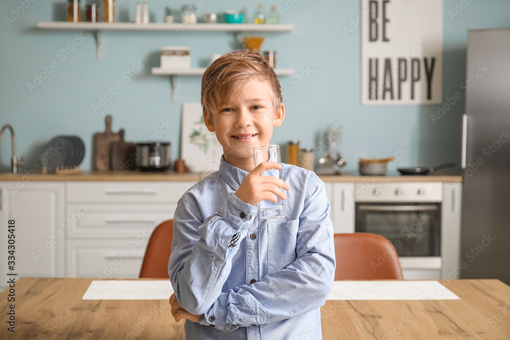 Cute little boy drinking water in kitchen