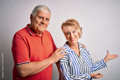 Senior beautiful couple standing together over isolated white background Inviting to enter smiling natural with open hand