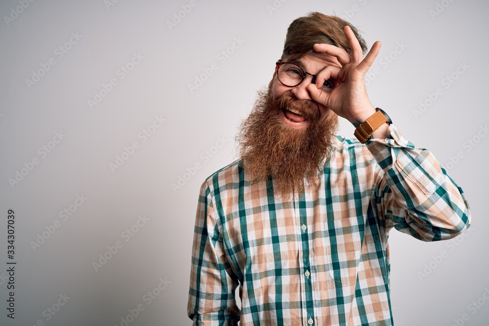Handsome Irish redhead man with beard wearing glasses and hipster shirt doing ok gesture with hand smiling, eye looking through fingers with happy face. Handsome Irish redhead man with beard wearing glasses and hipster shirt doing ok gesture with hand smiling, eye looking through fingers with happy face.