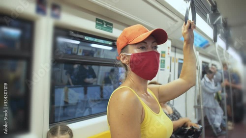 Woman travel caucasian ride at overground train airtrain with wearing protective medical red mask. Girl tourist at airtrain with respirator. Pandemic virus Coronavirus covid-19. People in mask. photo