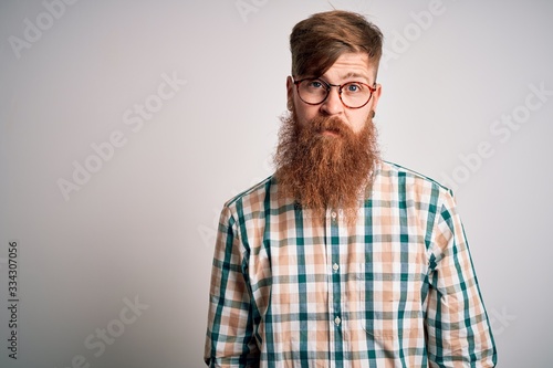 Handsome Irish redhead man with beard wearing glasses and hipster shirt with serious expression on face. Simple and natural looking at the camera. © Krakenimages.com
