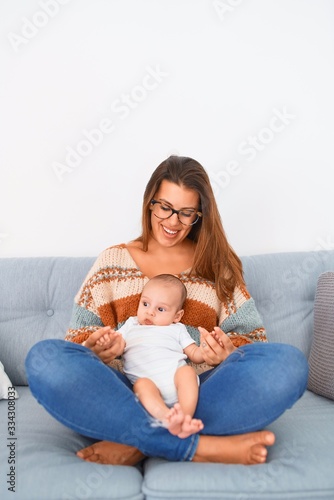 Young beautiful woman and her baby on the sofa at home. Newborn and mother relaxing and resting comfortable