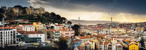 Stunning dramatic sunset over Lisbon, Portugal, seen from the Miraduro da Graca panoramic viewpoint in Alfama district, over the castle of Sao Jorge, the river Tagus and the bridge 25 de abril