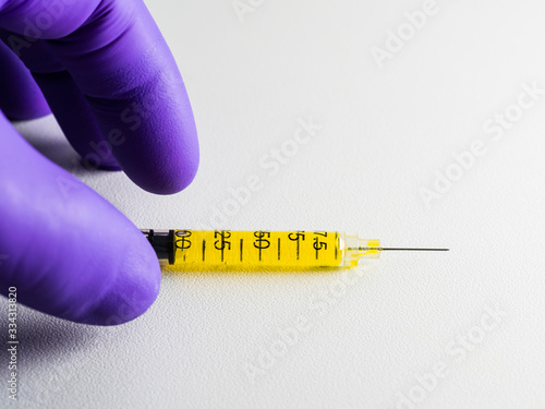 Obraz na płótnie Purple-gloved hand picks up a syringe on a white background