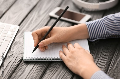 Woman writing something in notebook at table