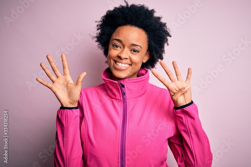 Young African American afro sportswoman with curly hair wearing sportswear doin sport showing and pointing up with fingers number nine while smiling confident and happy. photo