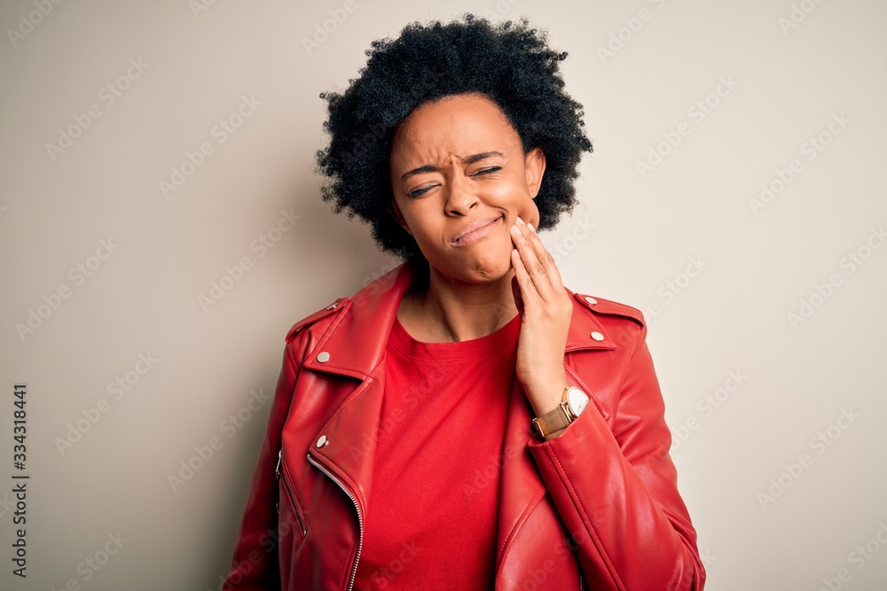 Young beautiful African American afro woman with curly hair wearing casual red jacket touching mouth with hand with painful expression because of toothache or dental illness on teeth. Dentist Young beautiful African American afro woman with curly hair wearing casual red jacket touching mouth with hand with painful expression because of toothache or dental illness on teeth. Dentist